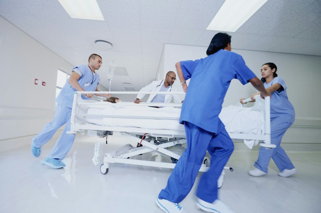 Doctor and medical running with patient bed in hospital emergency