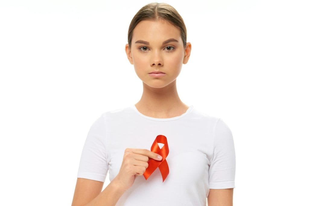 Girl with a red ribbon in the hands of a charitable foundation caring for oncology treatment